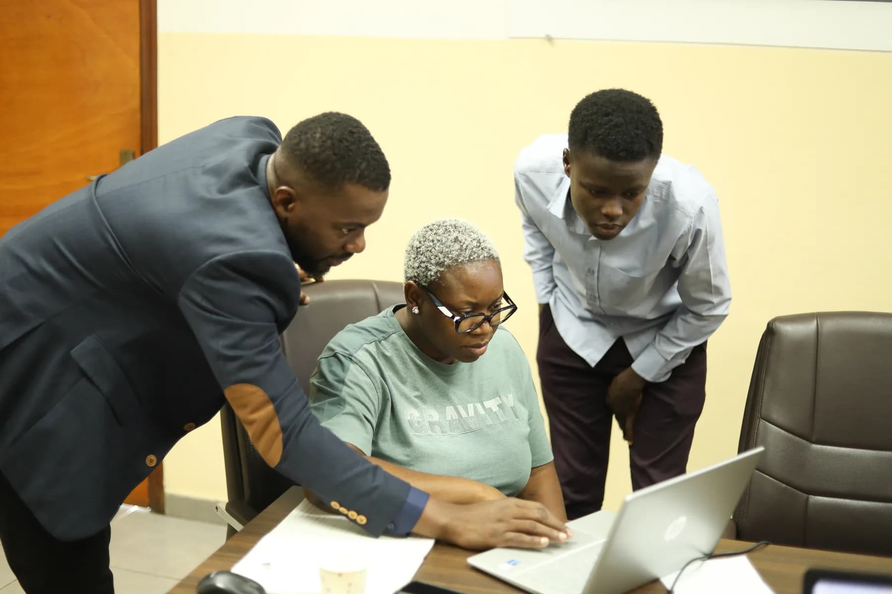 Deux intervenants Rx Lab aident une participante sur son ordinateur, lors d'une formation en entreprise.